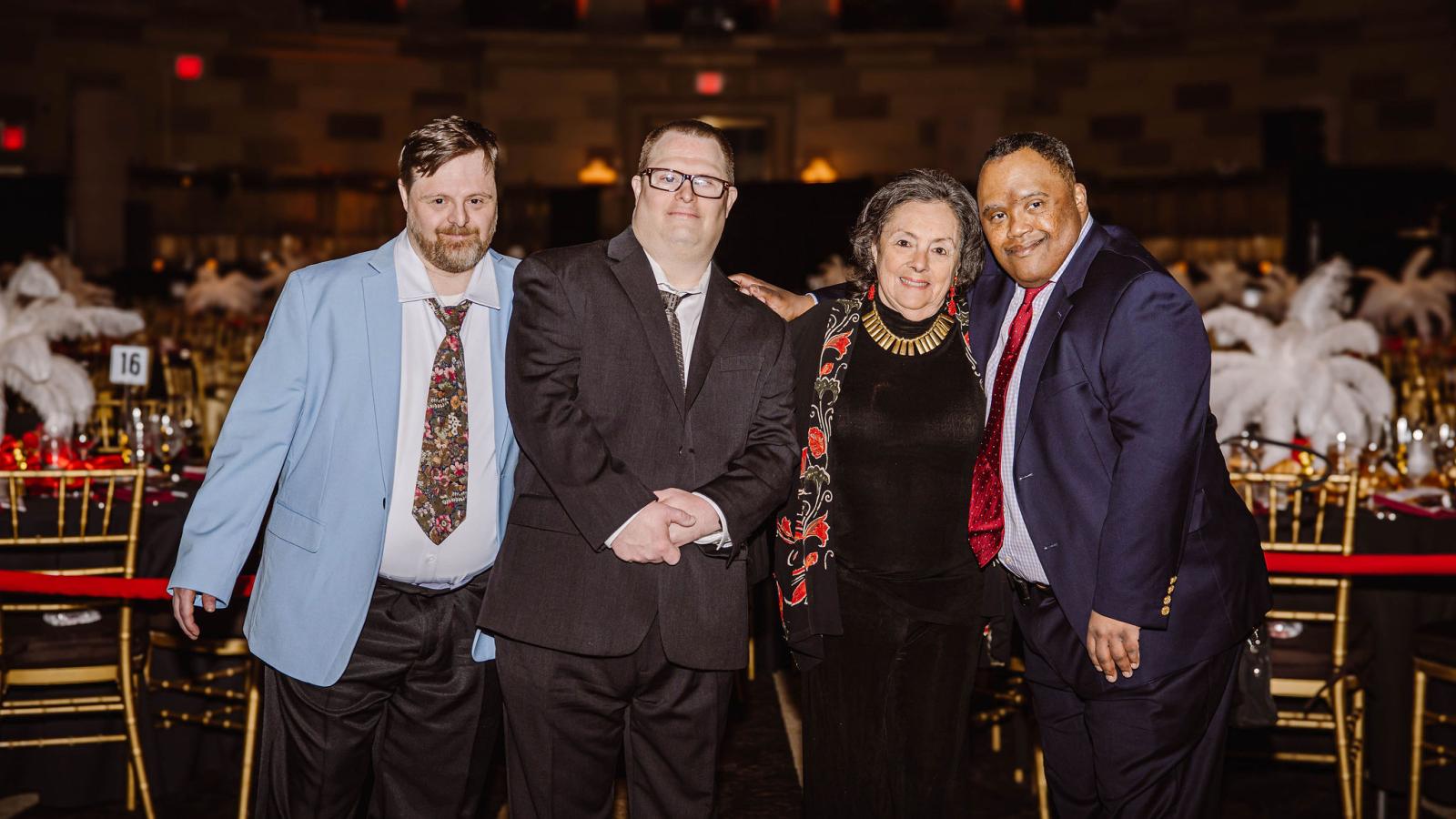 Four adults, with and without Down syndrome, smiling for the camera