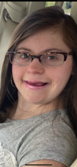 Elizabeth Sechrest headshot, brown hair, had Down syndrome and wears glasses