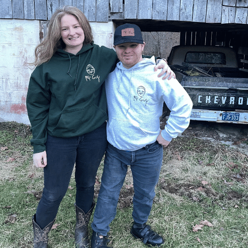 Marty, the business owner, stands in front of a black truck and sports his sweatshirt with a logo called my guy